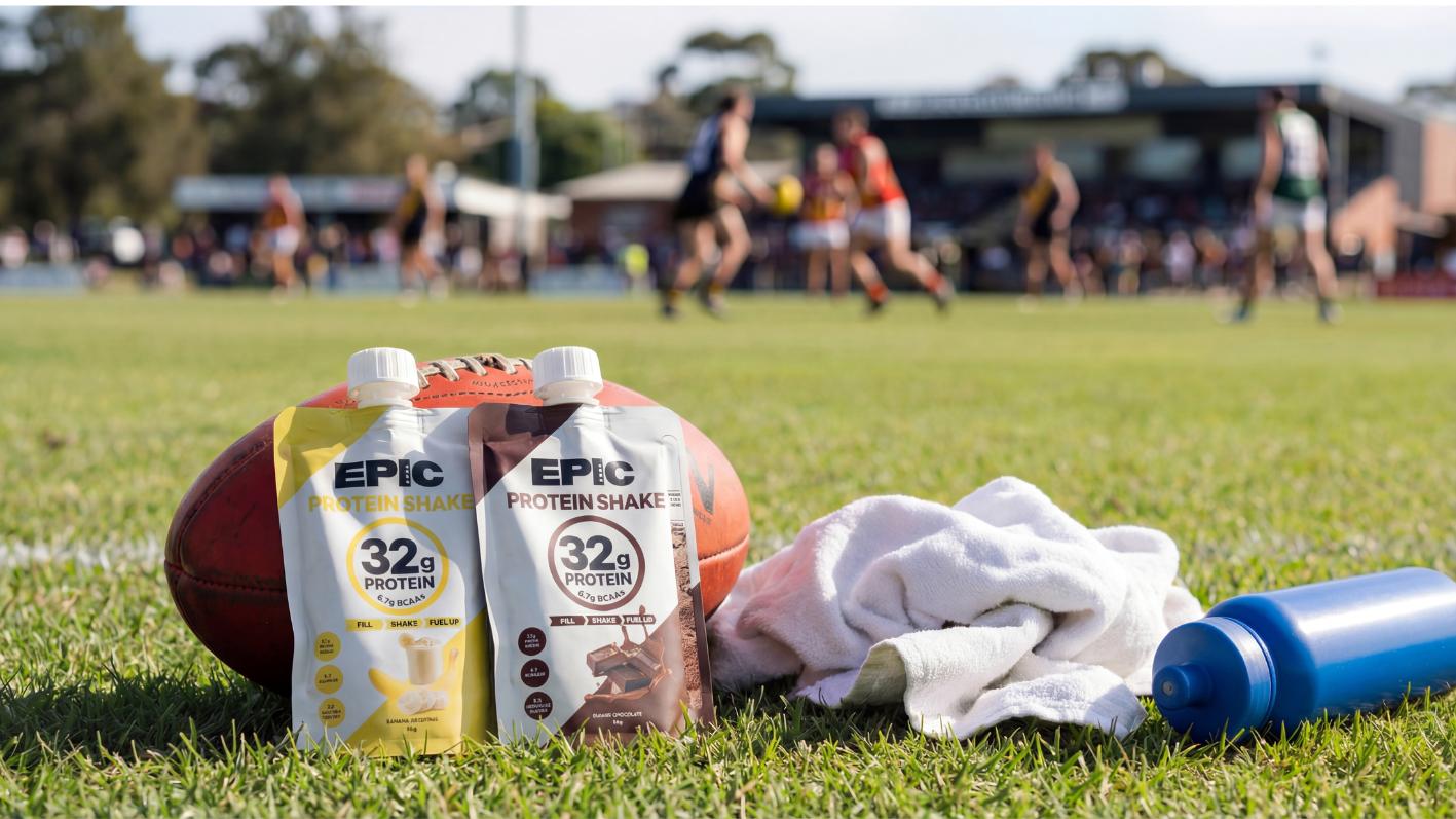 EPICmode protein shakes and Australian footy football sports equipment on a grass field with people training in the background